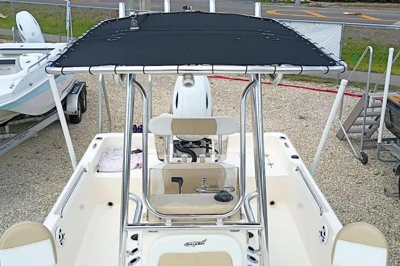 Slide: The Image of 2023 Bulls Bay 2200 boat with T-top and center console, parked on gravel. - 24