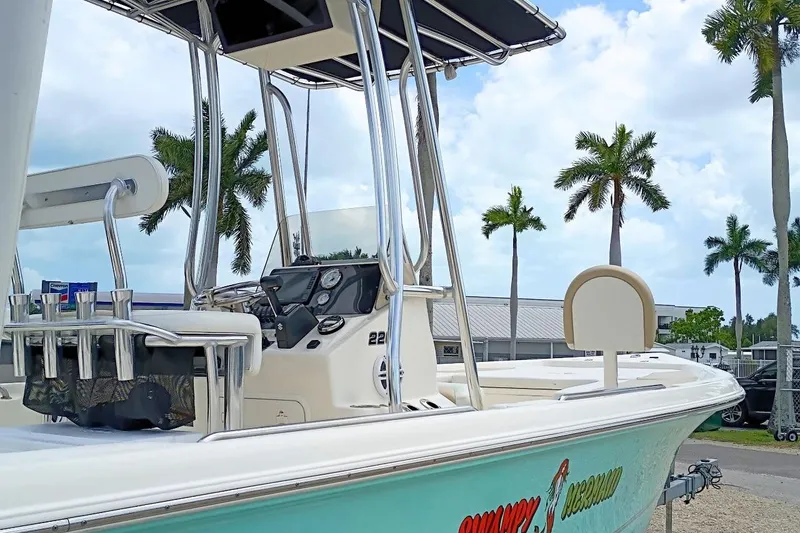 Slide: The Image of 2023 Bulls Bay 2200 boat with T-top, palm trees in background, sunny day. - 7