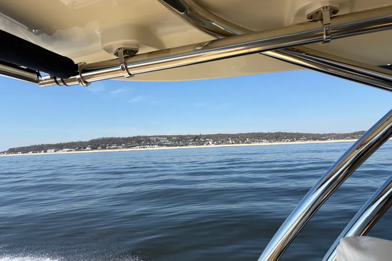 Slide: The Image of 2025 Chris Craft 28 Calypso boat cruising on calm waters with scenic shoreline view. - 13