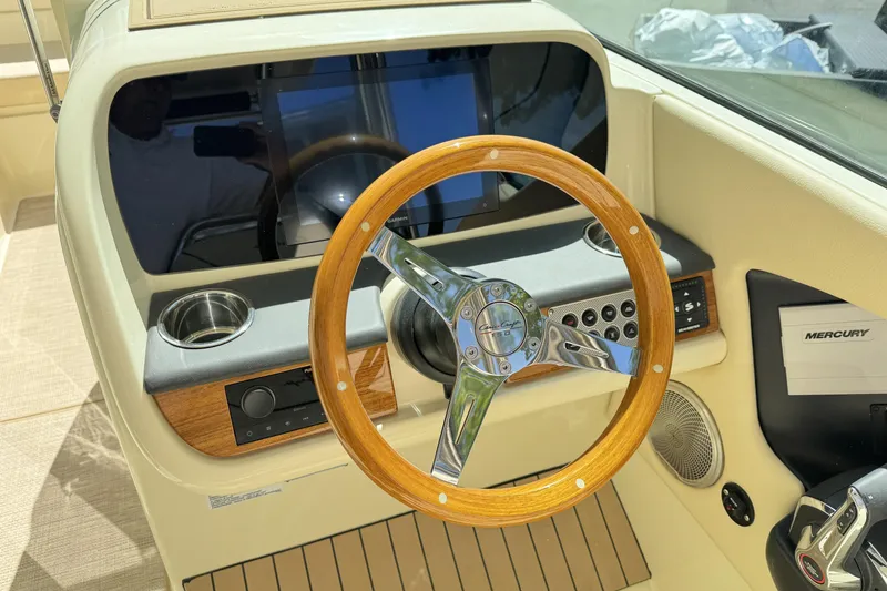 Slide: The Image of 2025 Chris-Craft Calypso 28 helm with wooden steering wheel and modern controls. - 19