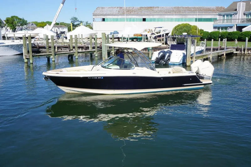 Slide: The Image of 2025 Chris-Craft Calypso 28 boat docked in a marina, featuring sleek design and dual engines. - 2