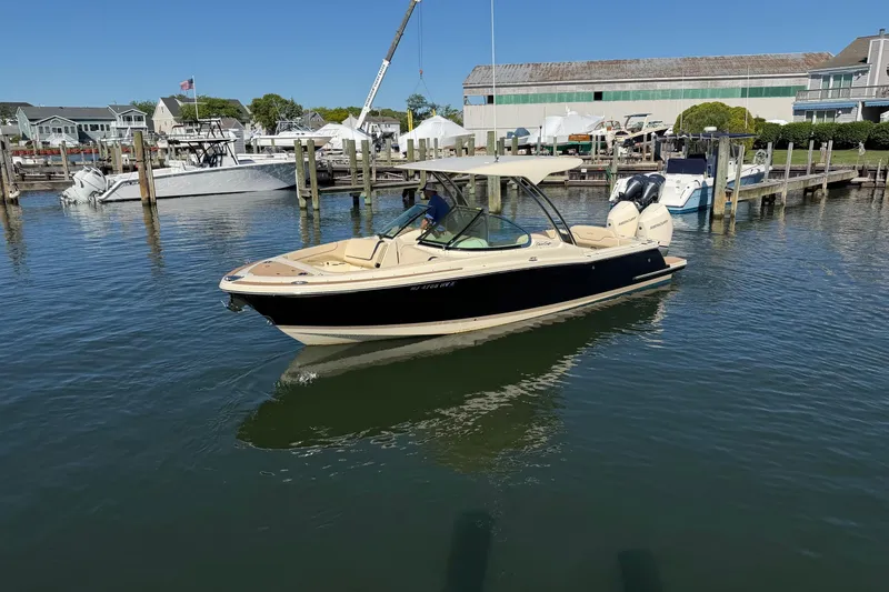 Slide: The Image of 2025 Chris-Craft Calypso 28 boat docked in a marina, showcasing sleek design and dual engines. - 3
