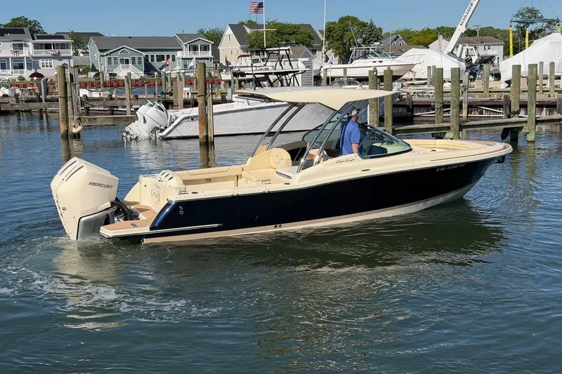 Slide: The Image of 2025 Chris-Craft Calypso 28 boat cruising in a marina with a Mercury engine. - 7