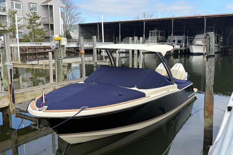 Slide: The Image of 2025 Chris Craft 28 Calypso boat docked, covered with navy blue tarp. - 8