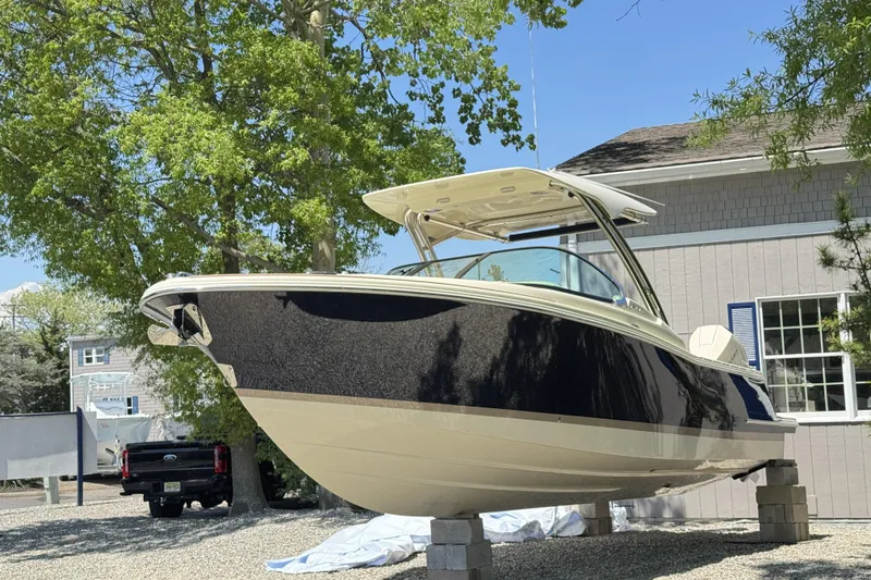 Slide: The Image of 2025 Chris-Craft Calypso 28 boat on display outdoors, surrounded by trees and buildings. - 9