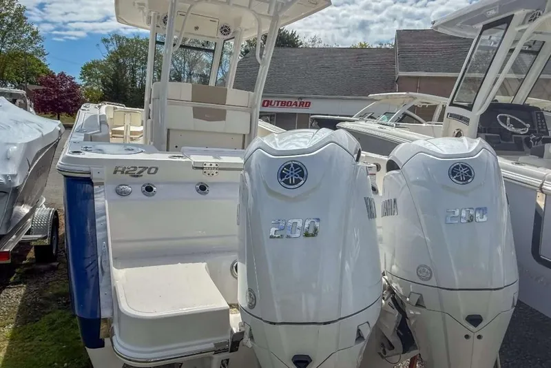 Slide: The Image of 2025 Robalo R270 Center Console boat with dual Yamaha 200 engines, docked outdoors. - 2