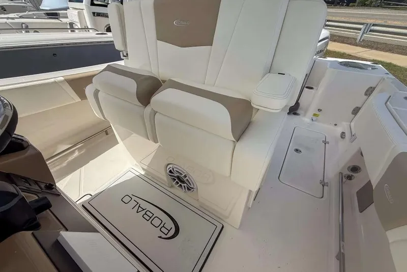 Slide: The Image of 2025 Robalo R270 Center Console boat interior with cushioned seating and branded flooring. - 5