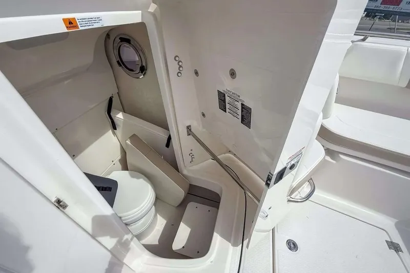 Slide: The Image of 2025 Robalo R270 Center Console boat interior with compact marine toilet. - 6