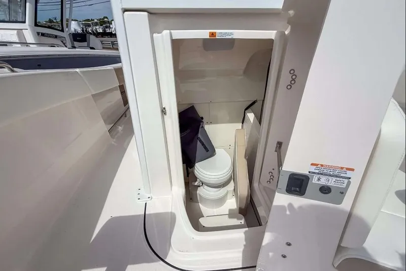 Slide: The Image of 2025 Robalo R270 Center Console boat interior with compact marine toilet. - 7