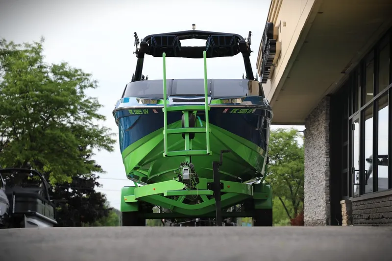 Slide: The Image of 2022 Centurion Ri265 boat in vibrant green and blue, parked outside a building. - 1