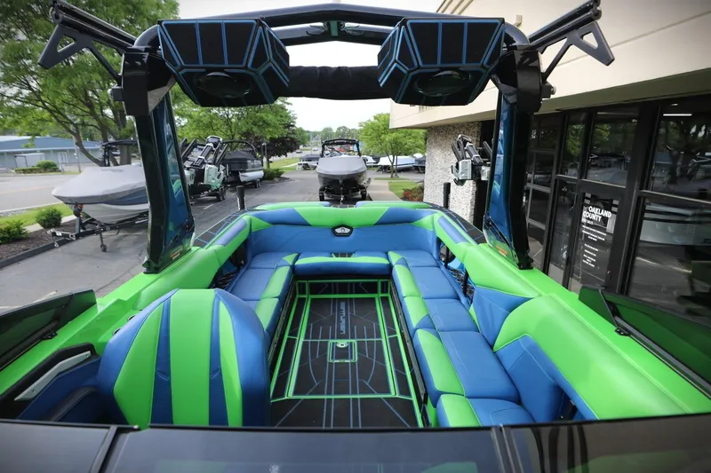 Slide: The Image of 2022 Centurion Ri265 boat interior with vibrant green and blue seating, docked outdoors. - 12