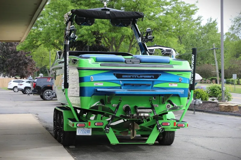 Slide: The Image of 2022 Centurion Ri265 boat in vibrant green and blue, parked on a trailer. - 16
