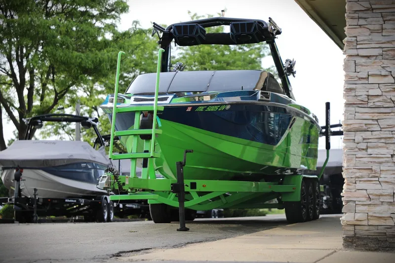 Slide: The Image of 2022 Centurion Ri265 boat in vibrant green on a trailer, parked outdoors. - 2
