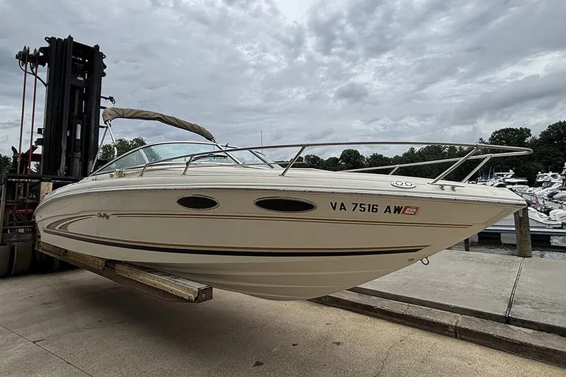 Slide: The Image of 2000 Sea Ray 230 Overnighter boat on forklift at marina, cloudy sky background. - 1