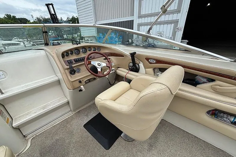 Slide: The Image of Interior of a 2000 Sea Ray 230 Overnighter boat with beige seating and dashboard. - 12