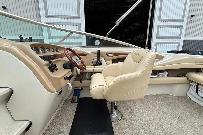 Slide: The Image of Interior of a 2000 Sea Ray 230 Overnighter boat with beige seating and dashboard. - 13
