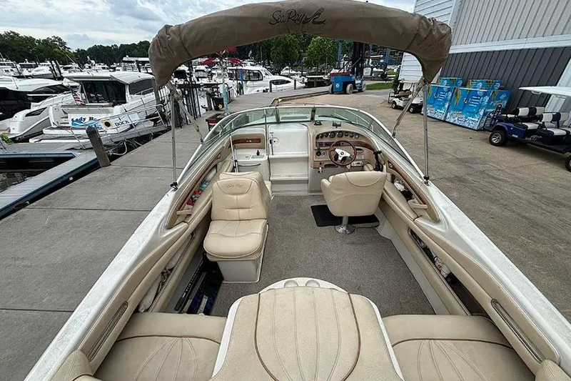 Slide: The Image of 2000 Sea Ray 230 Overnighter boat interior at marina, featuring beige seating and dashboard. - 8