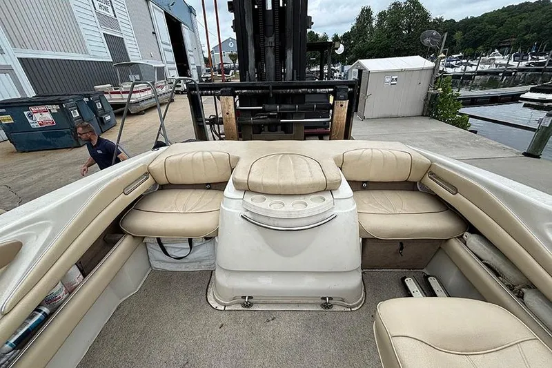 Slide: The Image of 2000 Sea Ray 230 Overnighter boat interior with beige seating at a marina. - 9