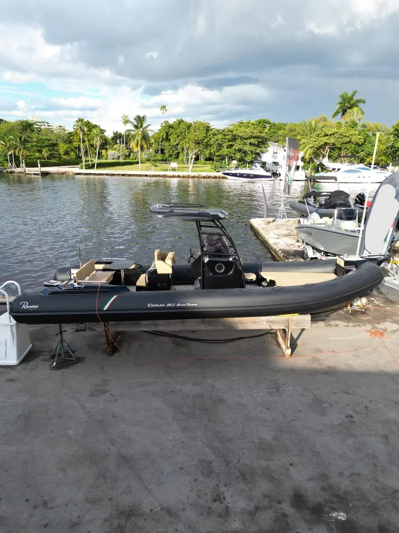 Slide: The Image of 2023 Ranieri CAYMAN 26 SPORT TOURING boat docked by a scenic waterfront. - 22