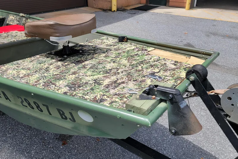 Slide: The Image of 1994 Alumacraft 1436 Jon boat with camouflage deck and brown seat on trailer. - 2