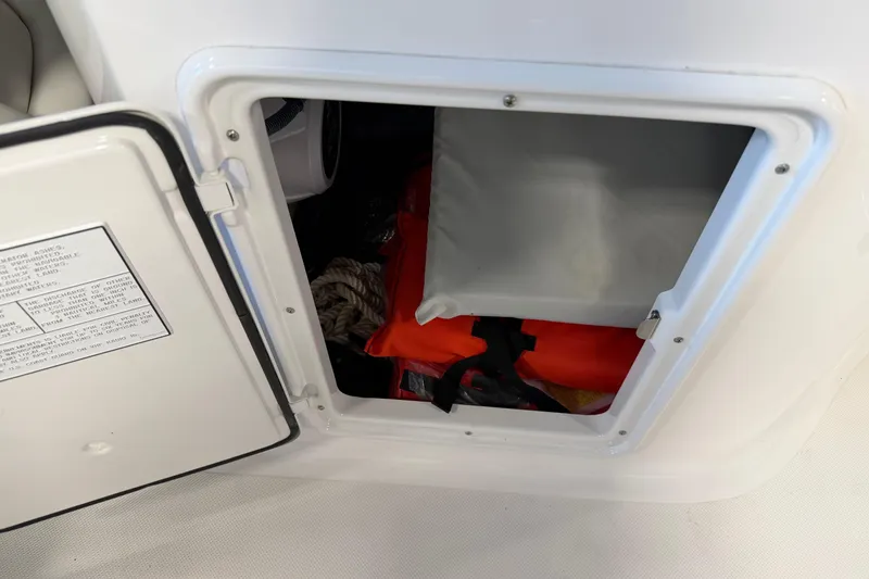 Slide: The Image of Open storage compartment on 2016 Regal 2550 Cuddy boat with safety equipment inside. - 18