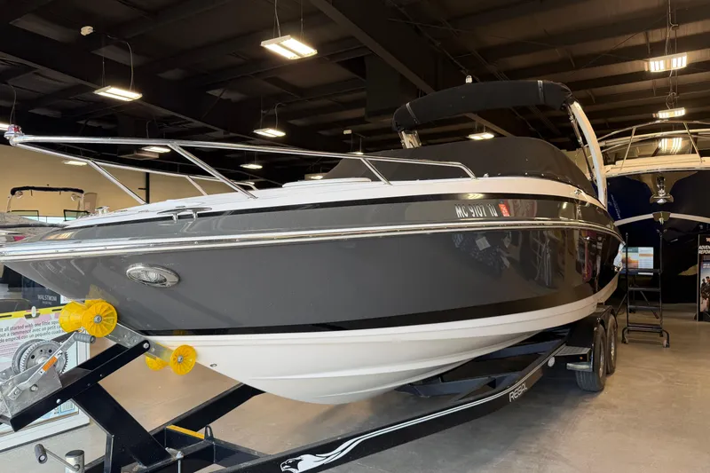 Slide: The Image of 2016 Regal 2550 Cuddy boat on trailer in showroom, sleek design, black and white exterior. - 8
