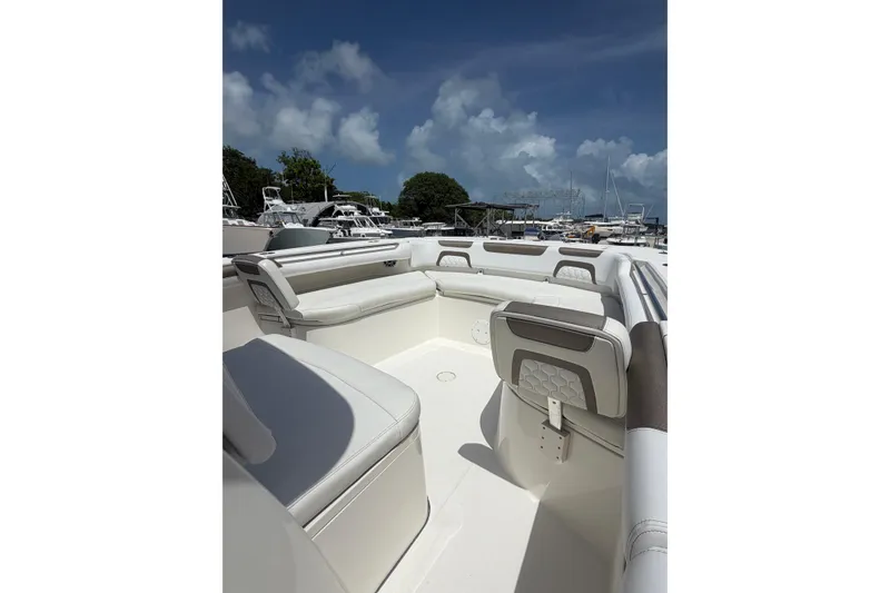 Slide: The Image of 2020 World Cat 325 CC boat interior with white seating, docked under a blue sky. - 12
