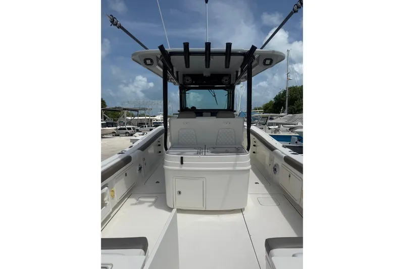 Slide: The Image of 2020 World Cat 325 CC boat interior with center console and seating, docked under a clear sky. - 7