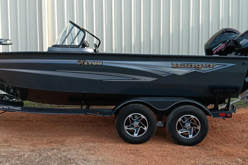 Slide: The Image of 2025 Ranger VX1788 WT boat on trailer, side view, parked on gravel. - 1