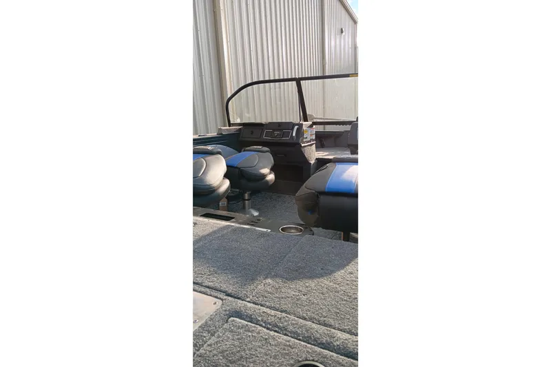 Slide: The Image of 2025 Ranger VX1788 WT boat interior with seating and console, parked near a metal building. - 7