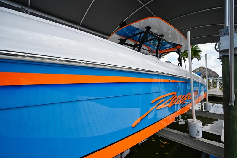 Slide: The Image of 2027 Renegade 38' Open boat with vibrant blue and orange design in marina. - 19