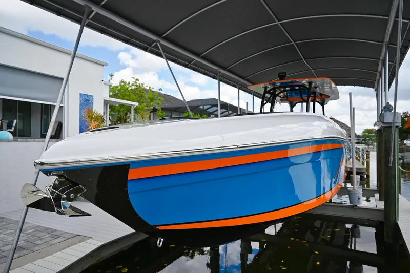 Slide: The Image of 2027 Renegade 38' Open boat with vibrant blue and orange design under a canopy. - 4