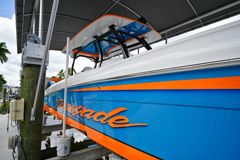 Slide: The Image of 2027 Renegade 38' Open boat with vibrant blue and orange design docked under a canopy. - 5
