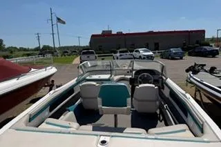 Slide: The Image of 1995 Four Winns 170 Freedom OB boat interior with seating and steering wheel in a parking lot. - 4