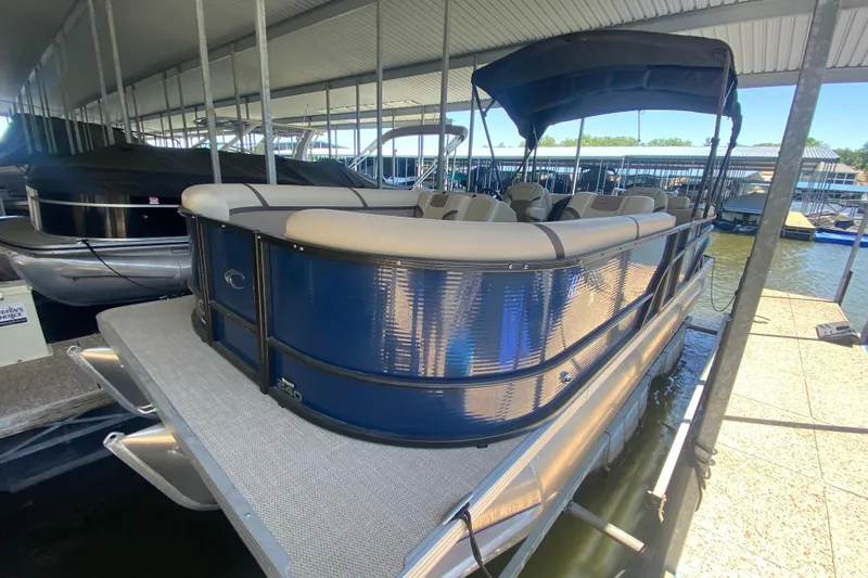 The Image of 2023 Crest Classic DLX 240 SLC pontoon boat docked under a covered marina. - 1
