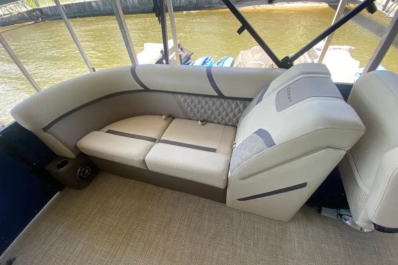 Slide: The Image of 2023 Crest Classic DLX 240 SLC boat interior with beige seating and quilted accents. - 10