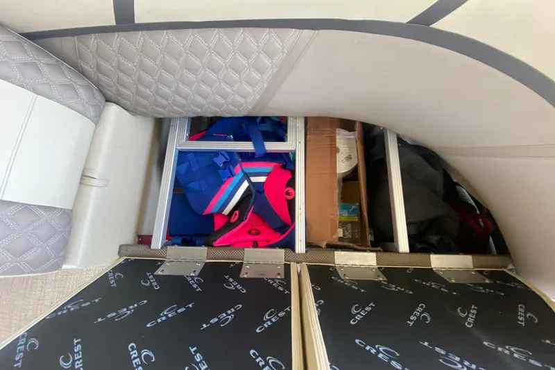 Slide: The Image of Storage compartment in 2023 Crest Classic DLX 240 SLC boat with life jackets and gear. - 12