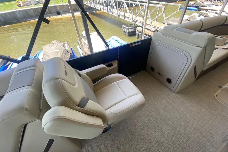 Slide: The Image of 2023 Crest Classic DLX 240 SLC boat interior with plush seating and dock view. - 13