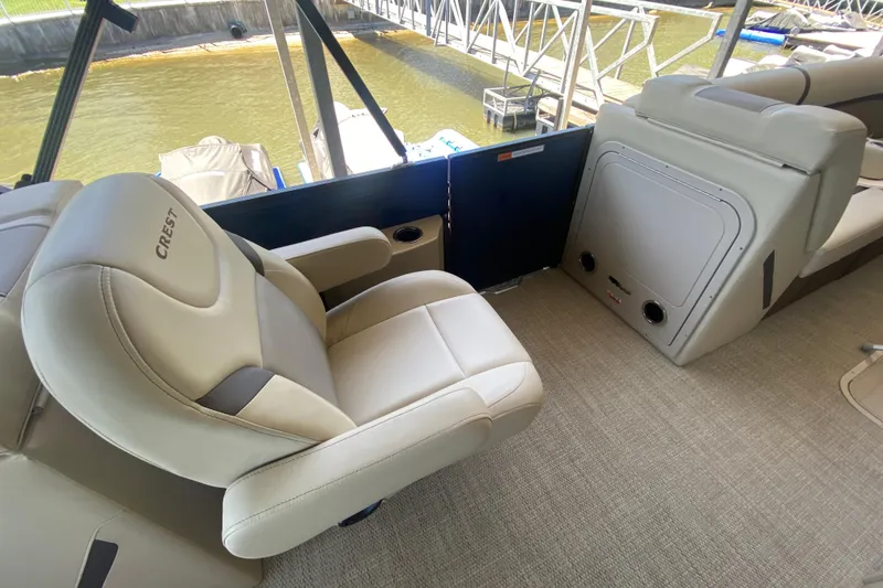 Slide: The Image of 2023 Crest Classic DLX 240 SLC boat interior with plush seating and lake view. - 14