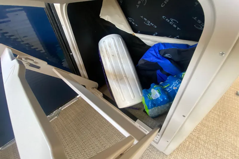 Slide: The Image of Storage compartment in 2023 Crest Classic DLX 240 SLC with supplies and water bottles. - 16