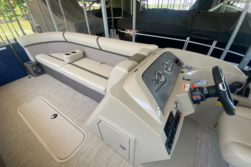 Slide: The Image of 2023 Crest Classic DLX 240 SLC boat interior with beige seating and steering console. - 23
