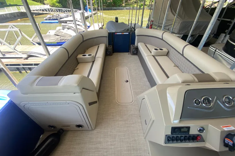 Slide: The Image of 2023 Crest Classic DLX 240 SLC pontoon boat interior with beige seating and control panel. - 24