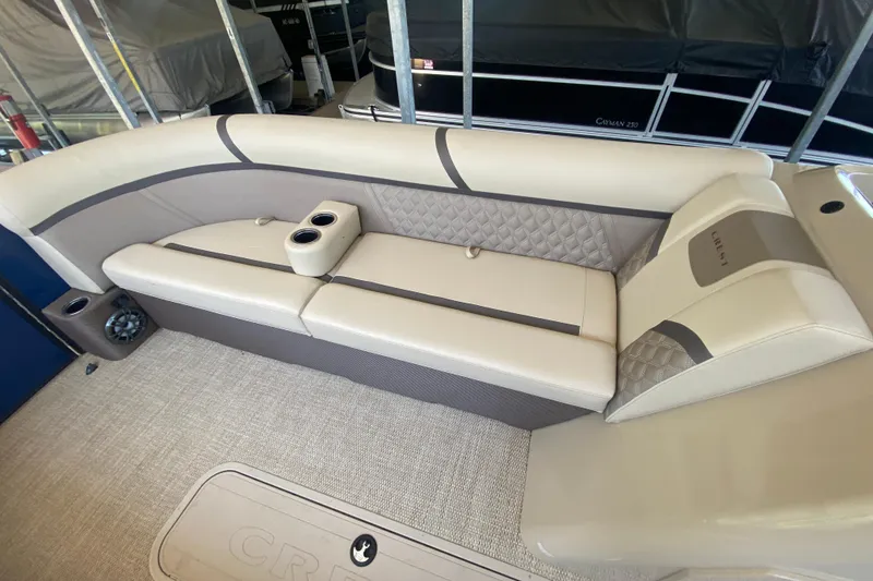Slide: The Image of 2023 Crest Classic DLX 240 SLC boat interior with beige seating and cup holders. - 26