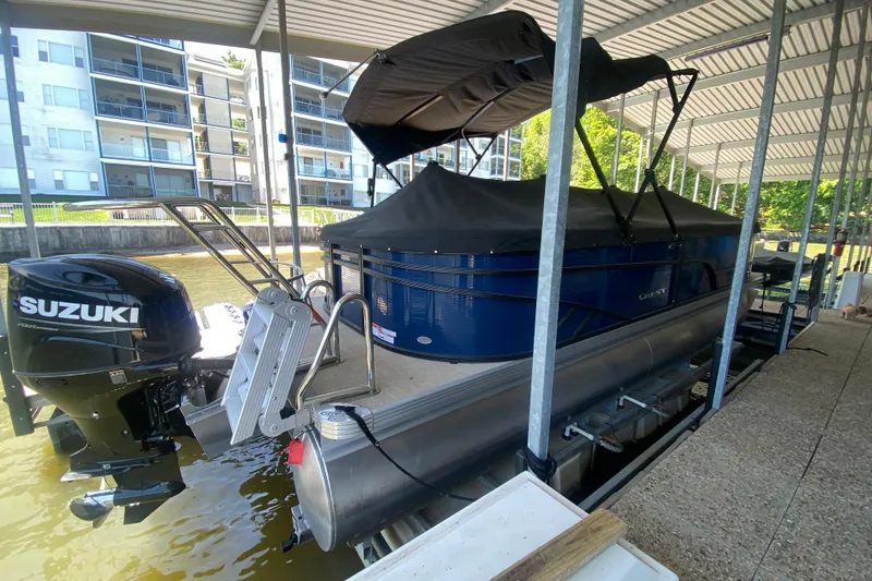 Slide: The Image of 2023 Crest Classic DLX 240 SLC pontoon boat docked with Suzuki outboard motor. - 31