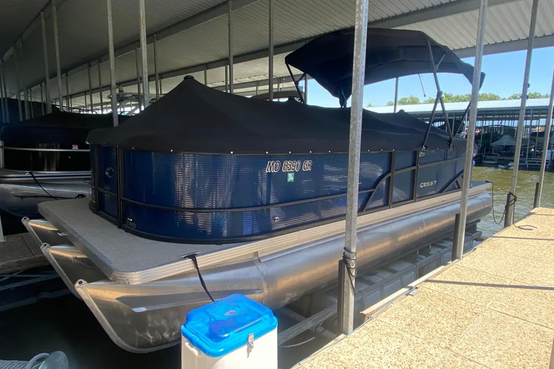 Slide: The Image of 2023 Crest Classic DLX 240 SLC pontoon boat docked under a covered marina. - 32