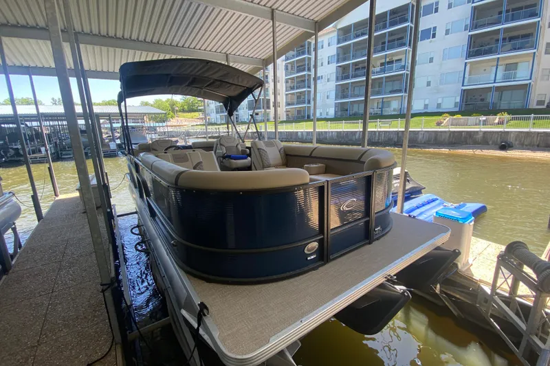 Slide: The Image of 2023 Crest Classic DLX 240 SLC pontoon boat docked under a covered marina. - 6