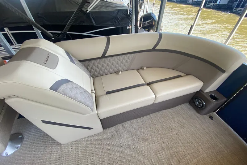 Slide: The Image of 2023 Crest Classic DLX 240 SLC boat interior with beige seating and quilted accents. - 9