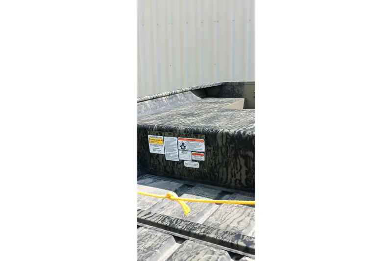 Slide: The Image of 2026 Tracker Topper 1542 LW Riveted Jon boat with camouflage pattern and safety labels. - 9
