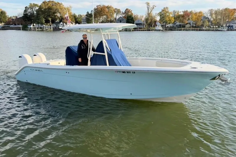 The Image of 2018 Cobia 277 Center Console boat on calm water, with trees in the background. - 0