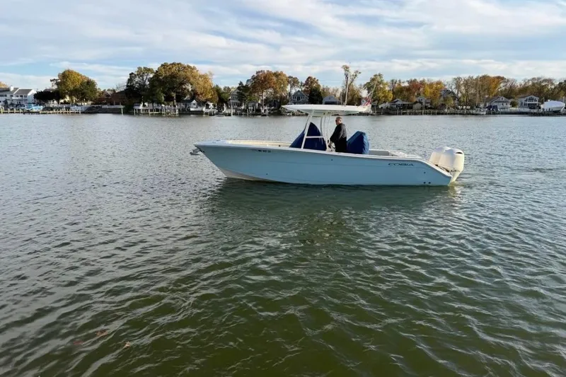 Slide: The Image of 2018 Cobia 277 Center Console boat on calm water, scenic shoreline background. - 1
